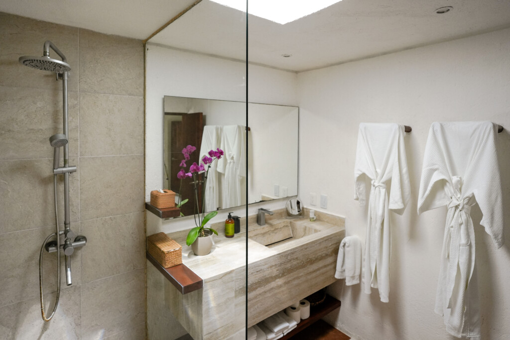 Baño principal estilo spa con batas y doble regadera en Casa Corazón